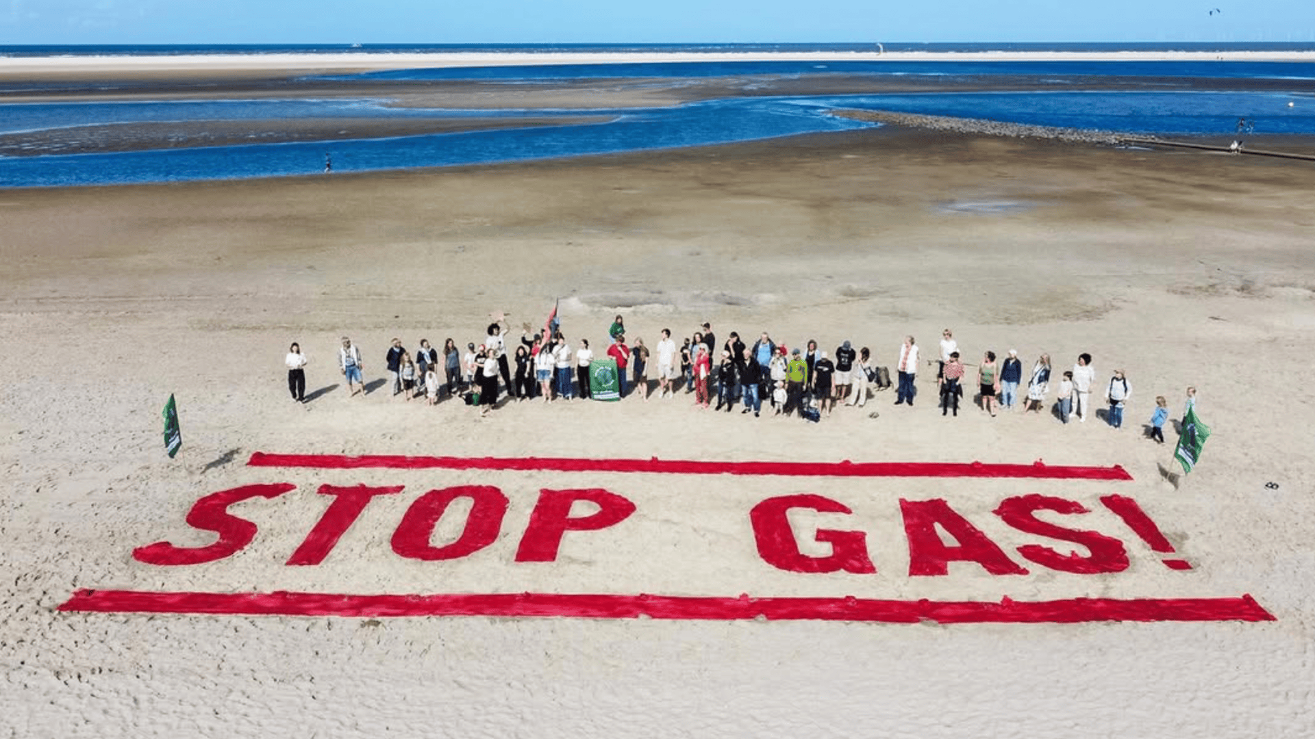 FFF-Aktivist*innen stehen am Strand von Borkum, vor ihnen ein Riesen Schriftzug in roten Farben, auf dem "STOP GAS" steht.